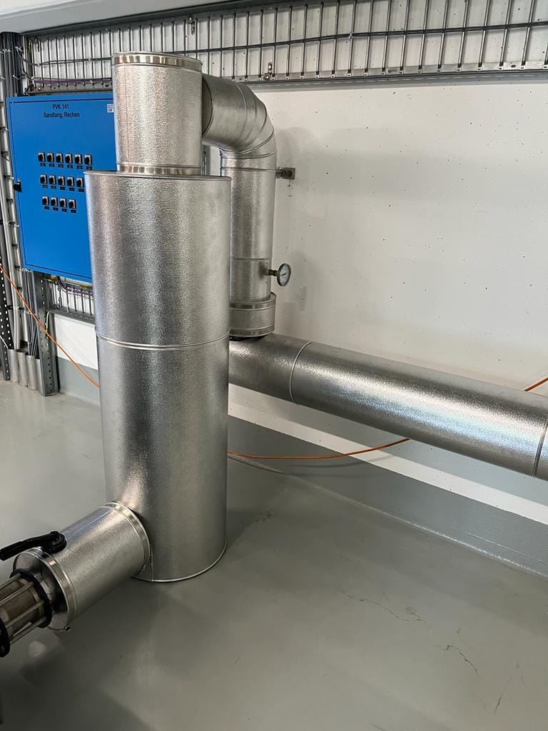Metallummantelte Isolierung an Rohrleitungen und einem senkrechten Anlagenbauteil